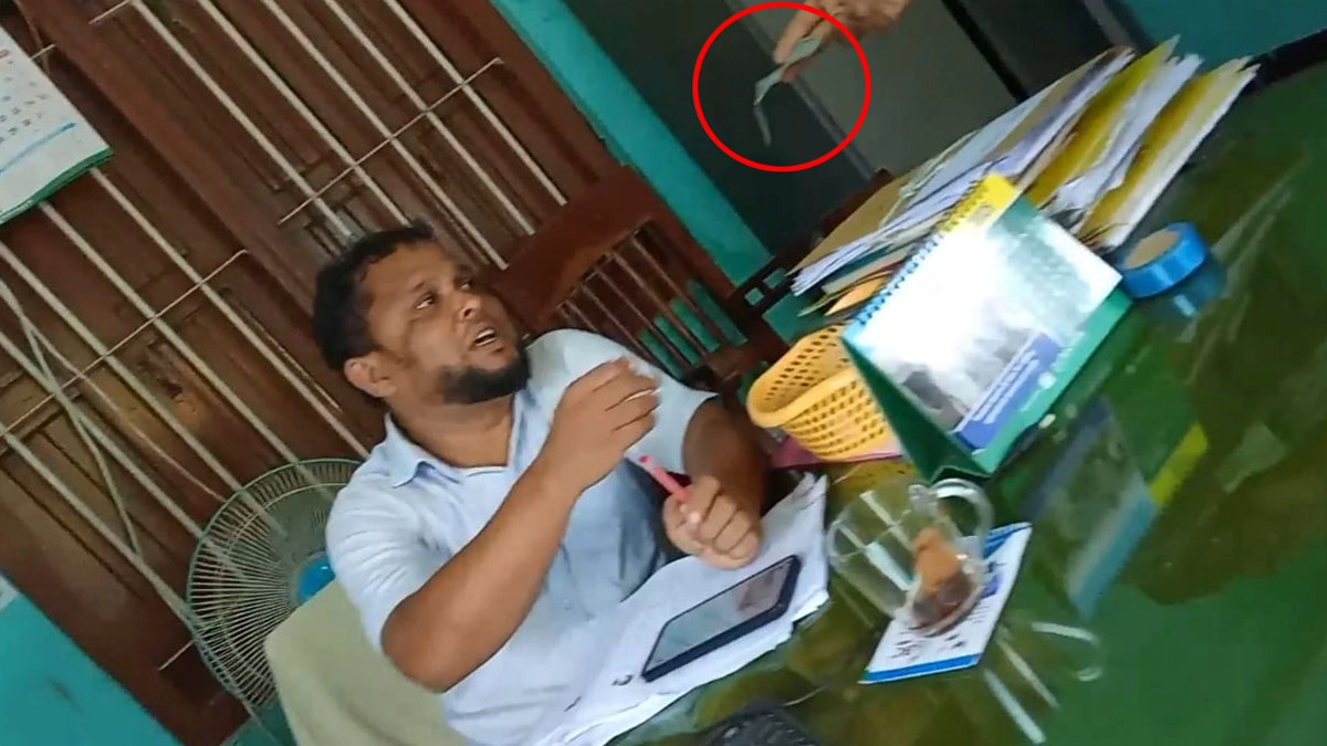 জহুরুল হক তার অফিস কক্ষে চেয়ারে বসে এক ব্যক্তির কাছ থেকে ৫০০ টাকার নোট গ্রহণ করছেন।     ছবি- সংগৃহীত