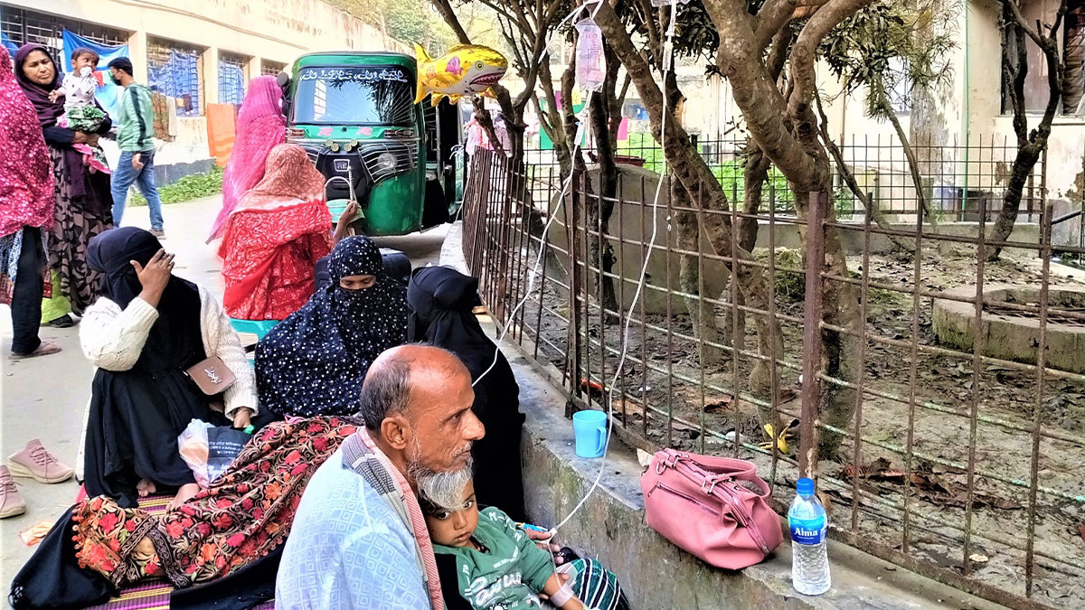 রোগীর অতিরিক্ত চাপে গাছের সঙ্গে স্যালাইন ঝুলিয়ে রোগীকে সেবা নিতে হচ্ছে। ছবি- রূপালী বাংলাদেশ